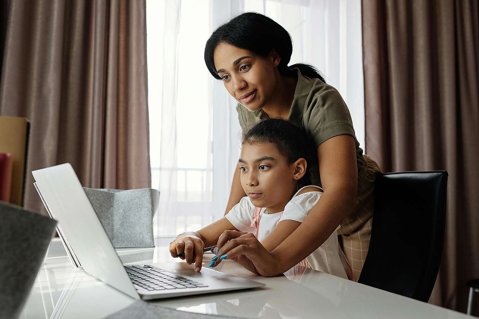 Mutter mit Tochter sitzen zusammen vor einem Laptop